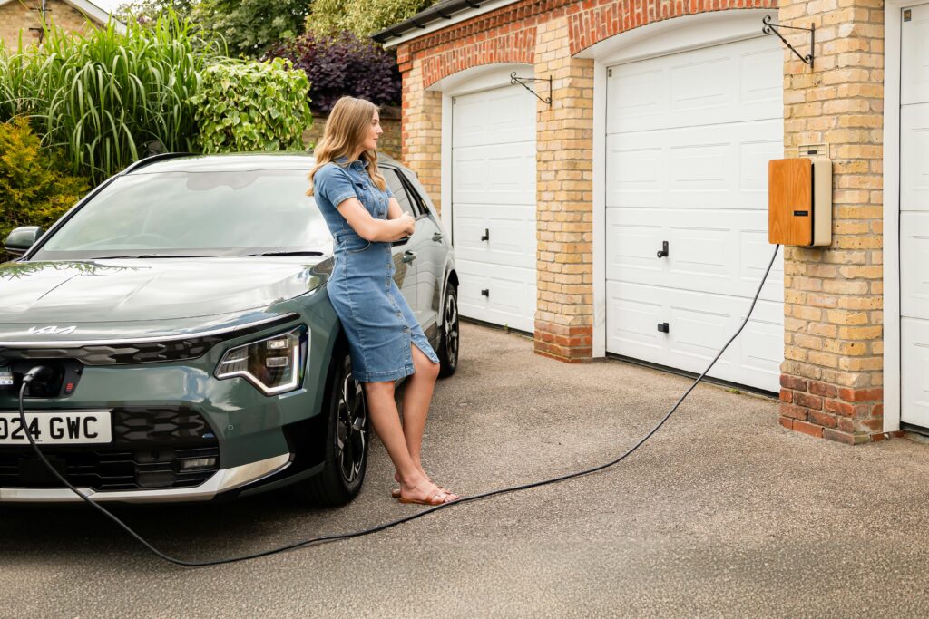 Woman standing in front of her home while her electric vehicle charges using a professionally installed in-home EV charging station in Essex County, New Jersey.